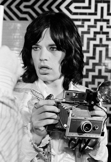 Mick Jagger takes a photograph on the set of ‘Performance’, Shepperton Studios, London, September 1968 by Baron Wolman
