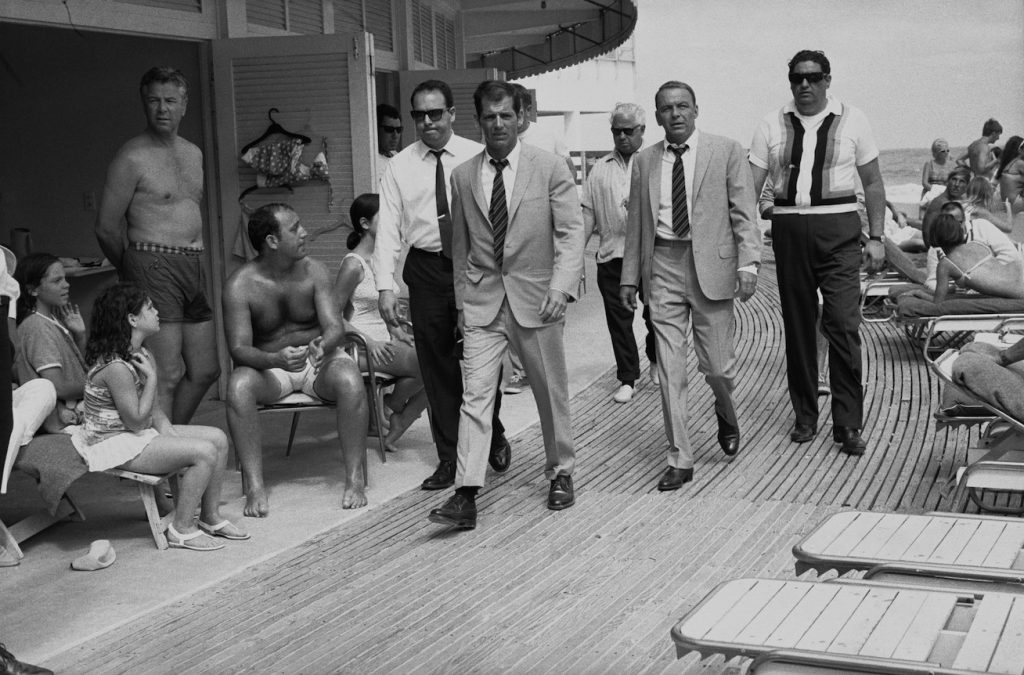 Singer and actor Frank Sinatra, with his minders and his stand in (who is wearing an identical outfirt to him), arriving at Miami beach while filming, 'The Lady In Cement', 1968. (Photo by Terry O'Neill/Getty Images)